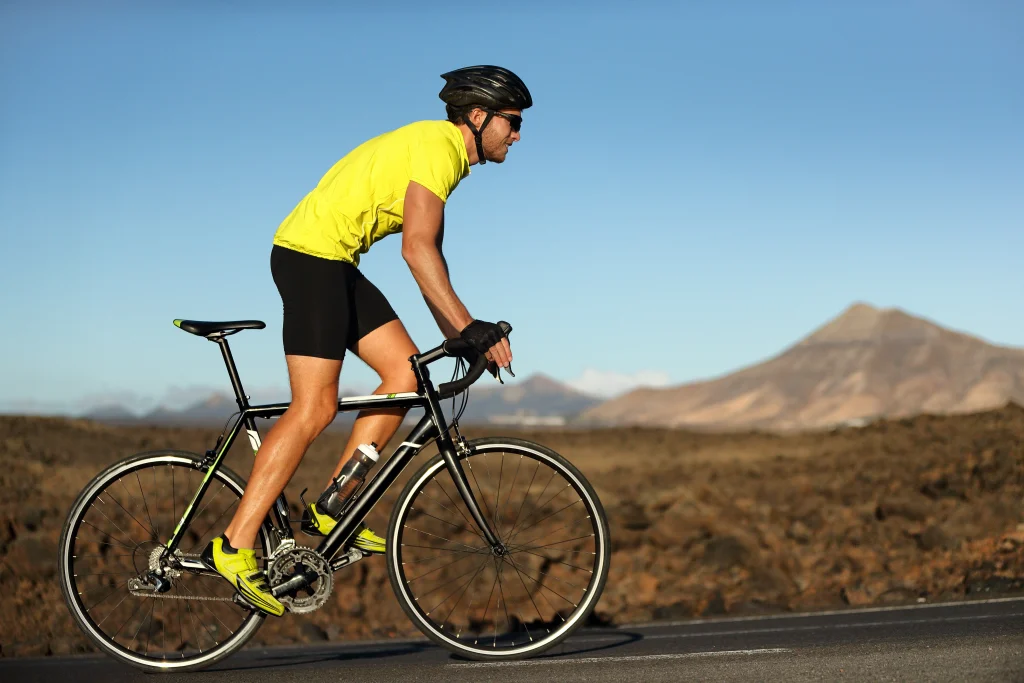 Cycliste sur un vélo de route en plein effort dans une région montagneuse.