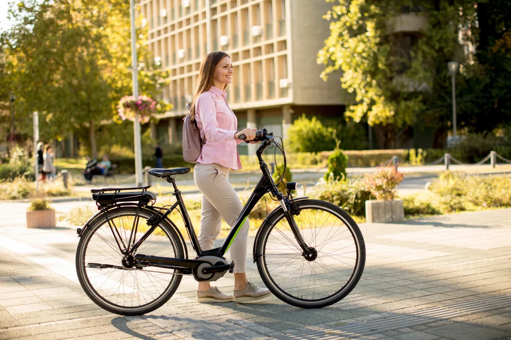 Femme marchant à côté de son vélo de ville électrique dans la rue.