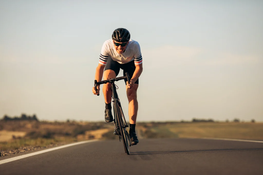 Cycliste sur route droite au couché de soleil en plein effort.