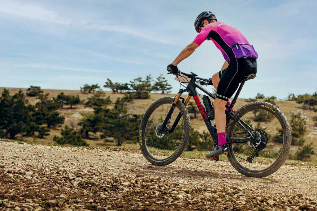 Femme sur un VTT BMC roulant sur un chemin montagneux.